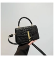 Détail d'un sac à main gaufré crocodile avec fermoir en métal doré et poignée supérieure - Noir