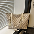 Beige Tragetasche mit M-Monogramm-Druck und goldenem Anhänger in modernem Ambiente - Weiß