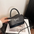 Piccola borsa a tracolla nera in pelle lucida con fiocco metallico argentato - Nero