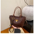 Détail du sac seau marron vintage avec logo métallique, gland tissé et bandoulière réglable - Café (Avec Pendentif)