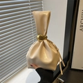 Sac seau beige avec poignée ronde et breloque dorée sur fond minimaliste et élégant - Blanc
