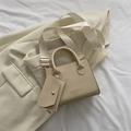 Beige faux leather crossbody bag with wide strap and mini pouch on minimalist background - Off White