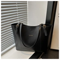 Detail of the black leather tote bag featuring gold FASHION & BAG lettering on the front - Black
