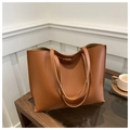 Detail of a brown leather tote bag with a metal buckle pocket on a wooden table - Brown