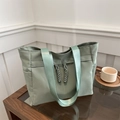 Minimalist light green nylon tote bag with decorative tassels on a wooden table - Green