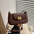 Brown puffy shoulder bag with golden chocolate lock and knotted strap on knit backdrop - Dark Brown