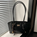 Chic black faux leather tote bag with gold logo plate and bell charm on handle - Black With Pendant
