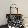 Leopard print tote bag set with matching pouch and brown handles on a book stack - Black