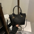 Bolso mini tipo cubo negro con herrajes dorados y asa con nudo en acabado brillante - Negro