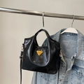Detailansicht der glänzenden schwarzen Textur und des goldenen Logos auf der Handtasche - Mit Anhänger / Schwarz