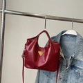 Detail der dunkelroten Lackleder-Tasche mit goldenem Logo und verstellbarem Schultergurt - Mit Anhänger / Burgunderrot