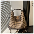 Detail der karierten Canvas-Tasche mit Plüschbären-Patch und Premium-Lederklappe - Braun