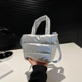 Detailed close-up of quilted silver padded tote bag with metallic finish and blue strap - Silver