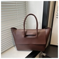 Detail of dark brown tote bag with cylindrical handles and matte leather texture - Coffee