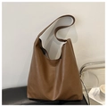 Detail view of a brown vintage PU leather tote bag placed on a sleek black chair - Brown