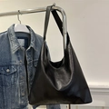 Minimalist black PU tote bag with a natural texture hanging next to a denim jacket - Black
