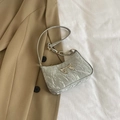 Silver pleated underarm bag featuring a metallic bow and chain strap on a blazer background - Silver
