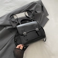 Minimalist black faux leather backpack featuring silver buckles on a grey blazer - Black