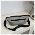 Close-up of lightweight light gray nylon crossbody bag with black zippers on a white desk - Green