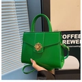 Detalle de bolso de cuero verde brillante con hebilla de trébol dorada y asa redonda - Verde