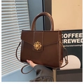 Detail view of dark brown trapezoid handbag with gold four-leaf clover metal buckle - Coffee