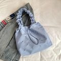 Light blue pleated tote bag with silver rivets and drawstring closure on white bedding - Blue