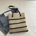 Dettaglio di borsa tote in paglia intrecciata con strisce nere e tracolle in pelle - Stile 1