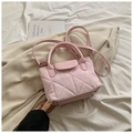 Detailed view of pink quilted handbag with gold-tone bottom studs and top handle - Pink
