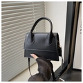 Close-up of a minimalist black leather square handbag with top handle and shoulder strap - Black