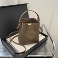 Deep brown matte bucket bag with integrated handle, long strap and golden snap closure - Brown