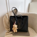 Black leather tote bag with lychee texture and plush bear pendant on a chair - With Pendant / Black