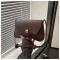 Detail of dark brown crocodile pattern handbag featuring a gold buckle and knotted strap - Coffee
