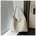 Detalle de la textura del bolso hobo blanco trenzado bajo luz solar suave y moderna - Blanco