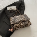 Chic leopard print crossbody bag with gold chain strap placed on a black blazer - Brown