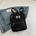 Mini sac à dos noir plissé avec nœud argenté décoratif présenté sur une veste denim - Noir