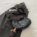 Bolso hobo negro de cuero granulado con herrajes dorados sobre fondo de traje gris - Negro