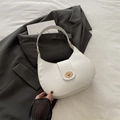 Sac bandoulière demi-lune blanc minimaliste avec fermoir doré sur une veste grise - Blanc