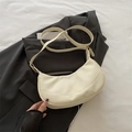 Elegante bolso de media luna en cuero crema con correa sobre una chaqueta blazer negra - Blanco