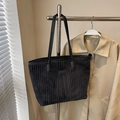Large black corduroy tote bag for women shown hanging over a beige trench coat - Black