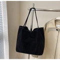 Detalle de un bolso tote grande de ante negro con bolsillo frontal colgado en una percha - Negro