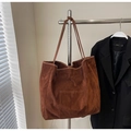 Primer plano detallado de bolso tote de ante marrón oscuro con bolsillo frontal decorativo - Marrón