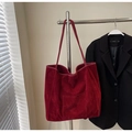 Detailed texture of red suede tote bag hanging on a rack with classic strap design - Burgundy