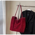 Detalle de bolso tote de terciopelo burdeos con bolsillo exterior colgado en una percha - Burdeos