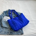 Quilted royal blue tote bag with puffer design on blue denim jacket and white background - Klein Blue