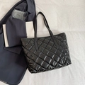 Elegante borsa tote nera trapuntata con design capiente su uno sfondo minimalista - Nero