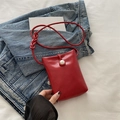 Red crossbody mini bag with pearl buckle and woven strap on a denim jacket - Red