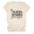 Dettaglio della maglietta beige con testo 'Be Your Own Kind of Beautiful' e stampa farfalla - S / Sabbia (Testo Nero)