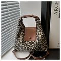 Detail of leopard print fabric tote bag with brown leather handles and metal hardware - Brown