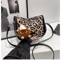Nahaufnahme der Schultertasche mit Leopardenmuster, Monster-Anhänger und schwarzem Gurt - Mit Anhänger / Khaki Leopard