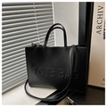 Detalle de letras TOTE BAG en relieve en un bolso tote grande negro de cuero sintético - Negro